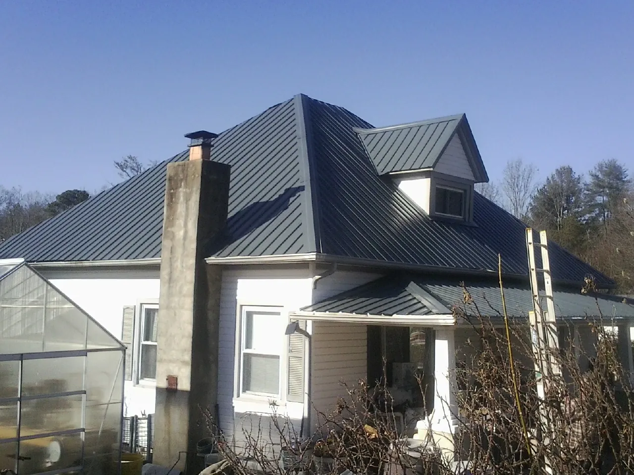 Dark blue standing seam metal roof on a white farmhouse with dormer — Slate & Tile Roof Repair by Roofing Brothers in Carpentersville