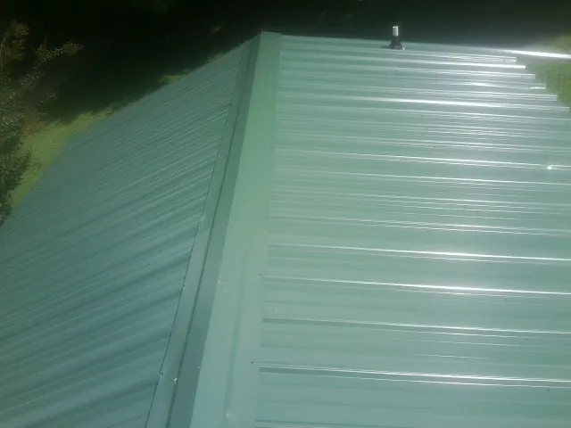 New green metal panels meeting at the ridge of a roof — Flat Roof Repair work by our crew in Carpentersville
