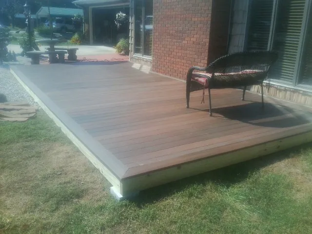 New wood deck and wicker chair beside a brick house in Carpentersville