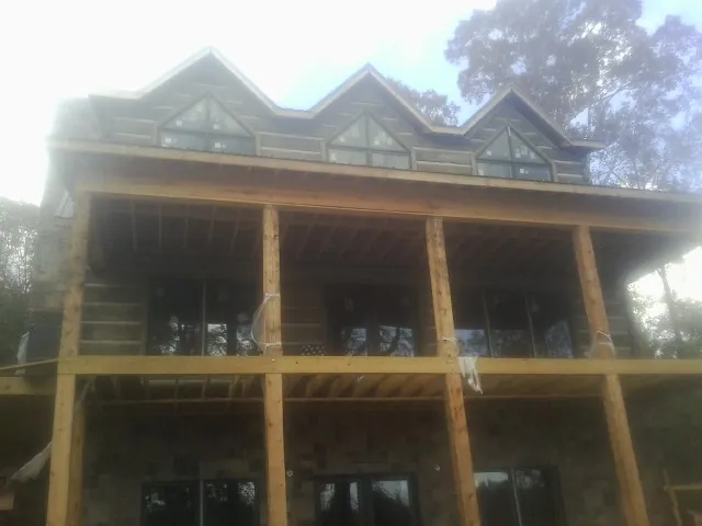 Dormers and porch framing on a large log home under construction — Roof Coating work by our crew in Carpentersville