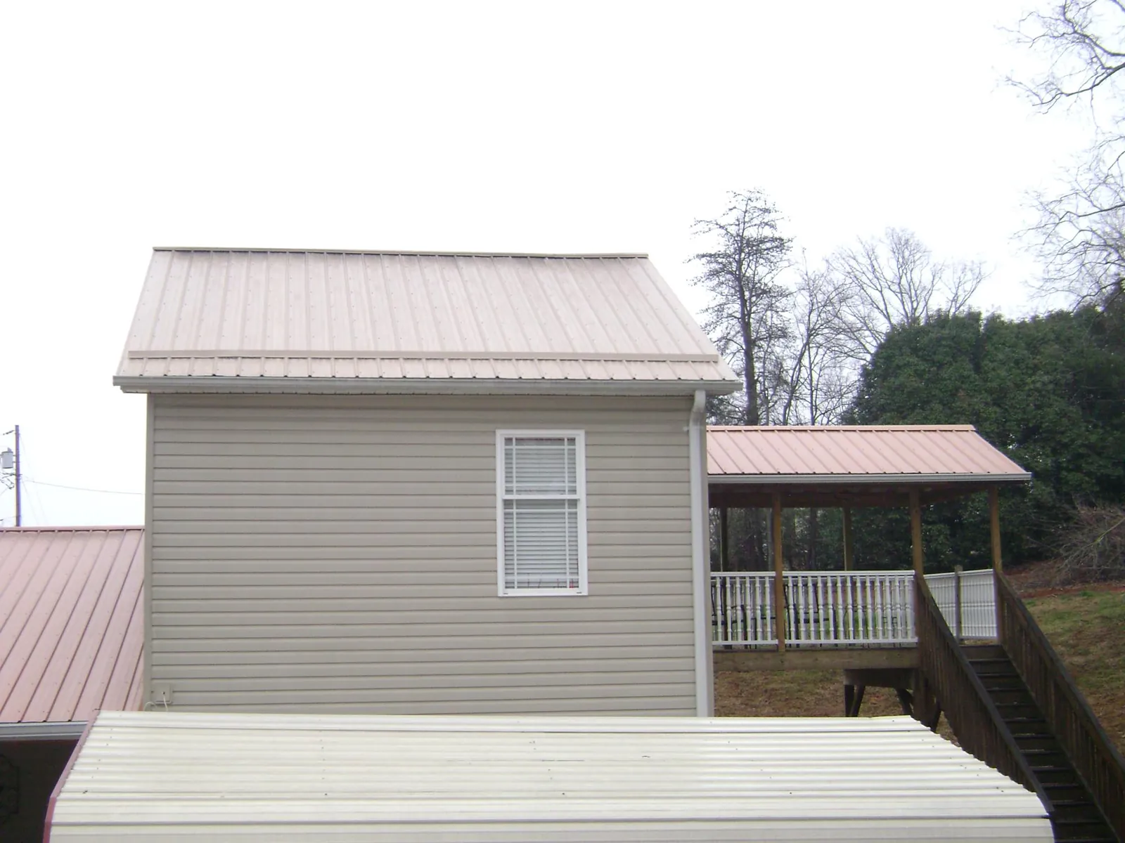 Tan metal roofs on a two story addition and attached porch, from a Roof Replacement job in Carpentersville