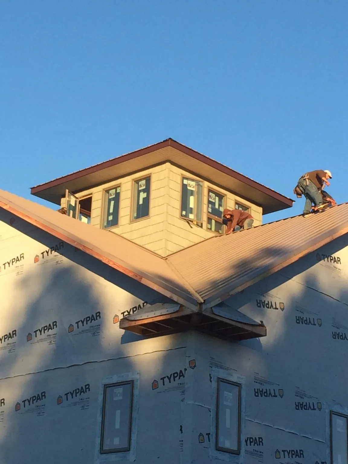 Roofers working around a rooftop cupola on a new metal roof at sunset — Roof Waterproofing in Carpentersville by Roofing Brothers